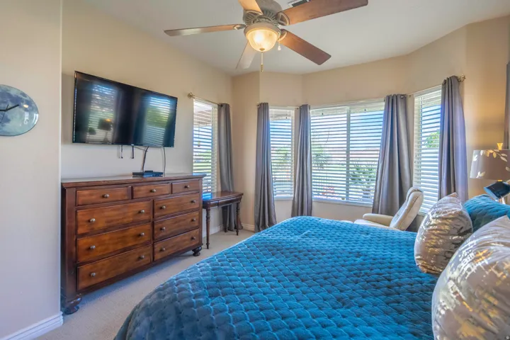 Tray ceiling with a ceiling fan, bay window with blinds and curtains, and carpet flooring