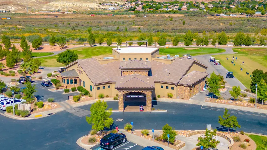 Golf clubhouse with public restaurant. Desert-toned building with stone accents, tile roofing, and a prominent covered entryway