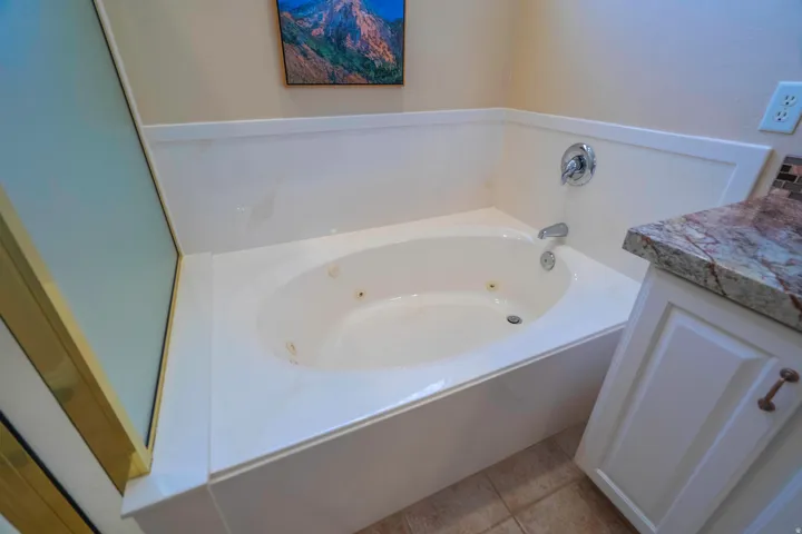 Luxurious soaking tub with integrated jets and dual faucet controls, set within a spacious alcove