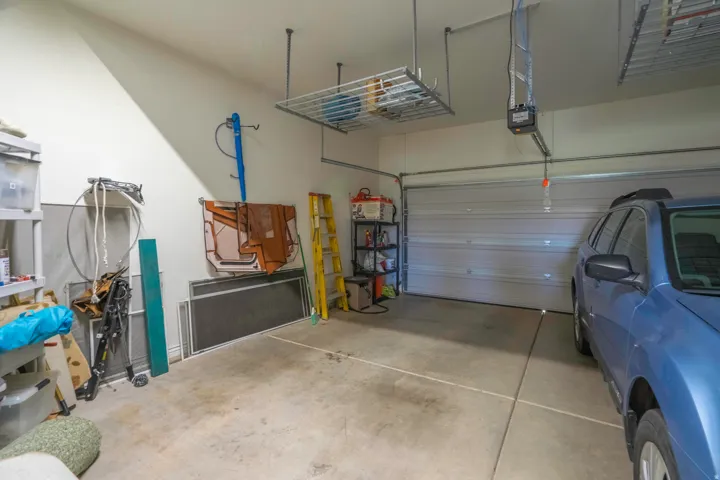 Spacious 2.5 car garage with concrete flooring, overhead storage racks, and an automatic garage door