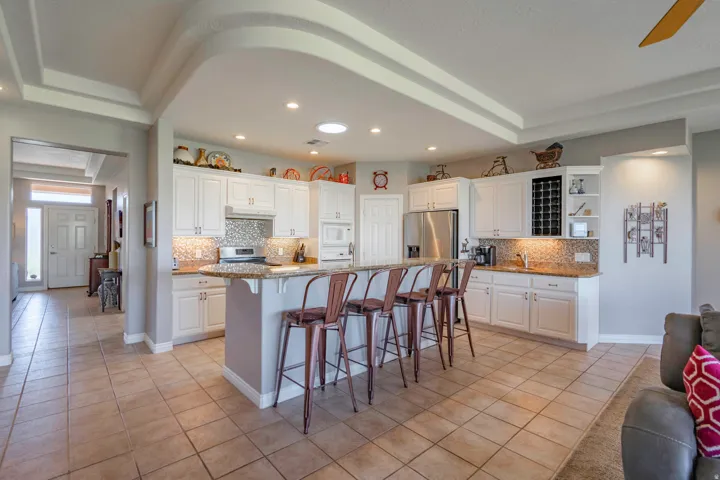 Kitchen featuring white cabinetry, granite countertops, tile flooring, and a breakfast bar