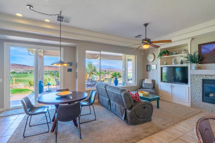 Open-concept living and dining area featuring tile flooring, a round dining table with seating for four, and expansive sliding glass doors opening to a covered patio