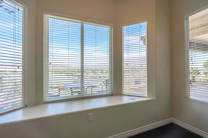 bonus room/art studio with bay window with a built-in window seat and multiple windows, dark wood-finish flooring, and white baseboards