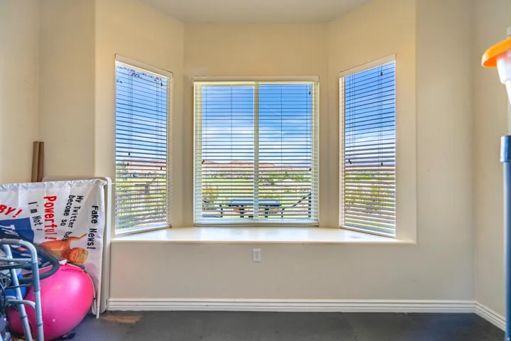 Bay window with a built-in window seat, multiple windows with horizontal blinds, and dark flooring in heated and air conditioned bonus room