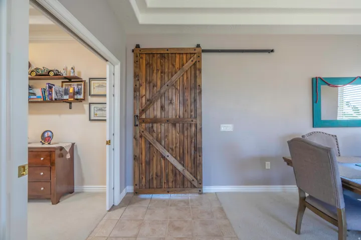Wood-finish barn door, separating formal living and family room & kitchen. Also, coffered ceiling, tile flooring, and carpeted flooring