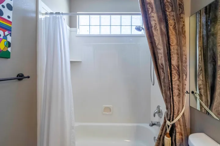 Clean, functional 2nd bathroom featuring a shower-tub combination with white subway tile surround, chrome fixtures, and a transom window providing natural light