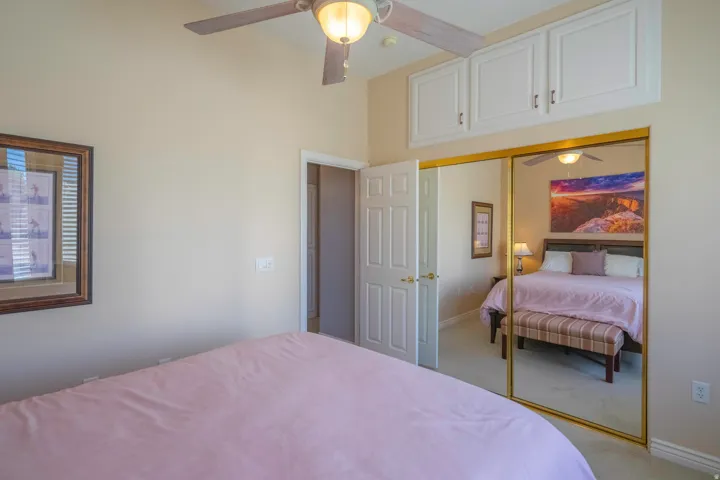 2nd Bedroom featuring mirrored closet doors with brass framing, ceiling fan with integrated lighting, white cabinetry with hardware accents, and plush carpeting throughout