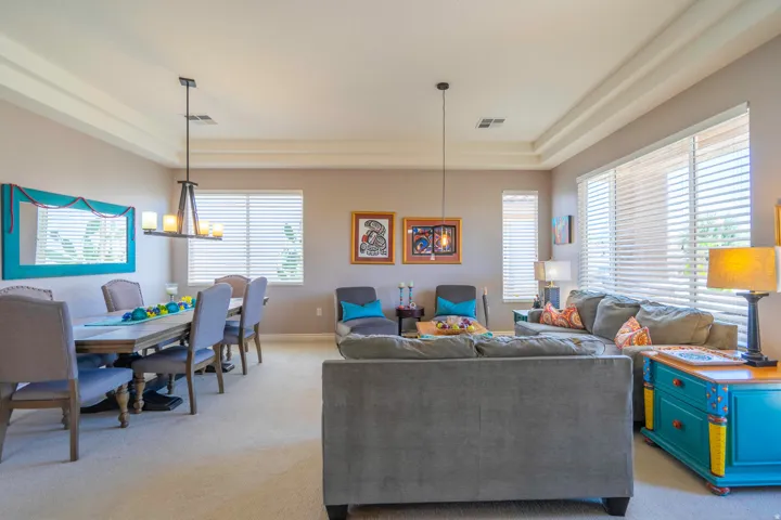 Spacious open-concept formal living area featuring a coffered ceiling, recessed lighting, and multiple windows with plantation shutters
