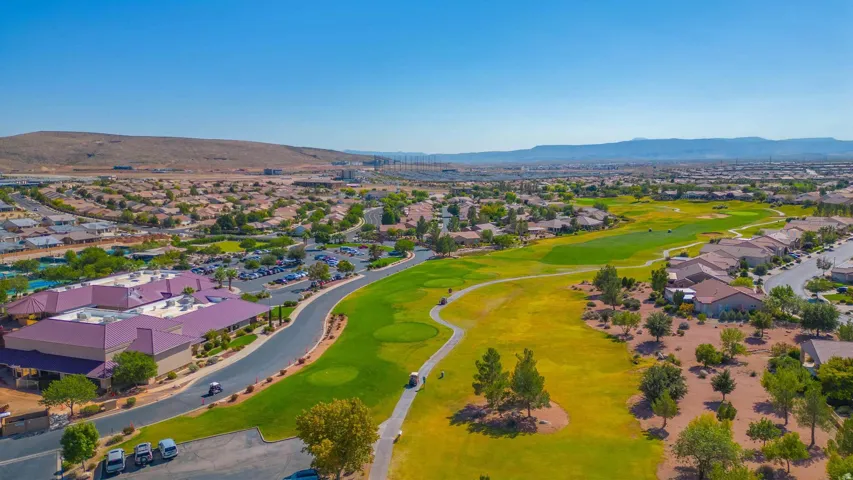 Aerial view showcasing expansive manicured grounds with vibrant turf, golf course, mature landscaping, and winding pathways