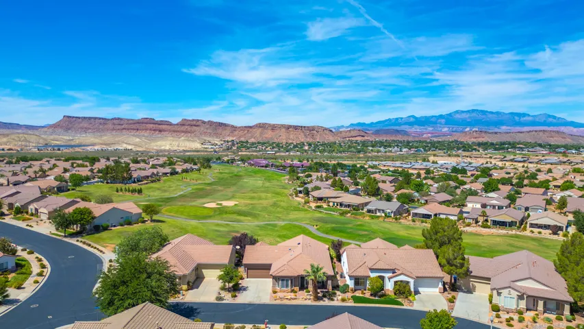 Aerial perspective showcasing residential properties with mountain backdrops, and a golf course