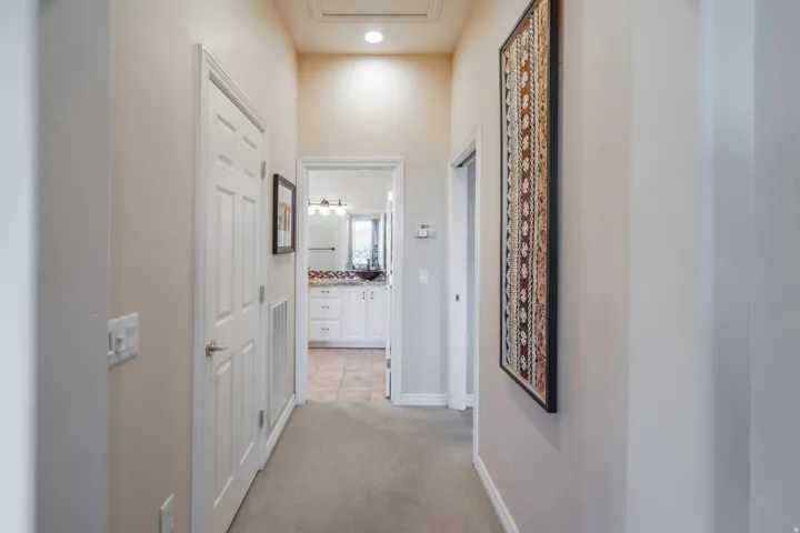 Carpeted hallway with a vaulted ceiling, recessed lighting, and white paneled doors