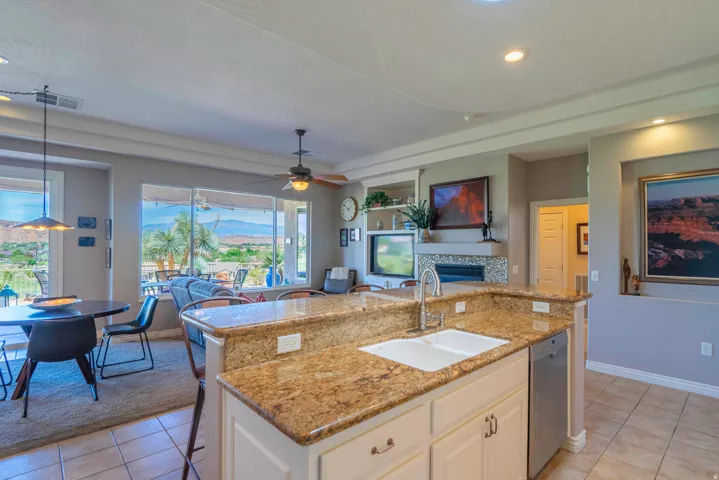 Kitchen island with granite countertops, double basin sink, and stainless steel dishwasher