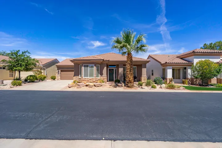Single-story residence featuring a tile roof, stone accents, and an attached garage