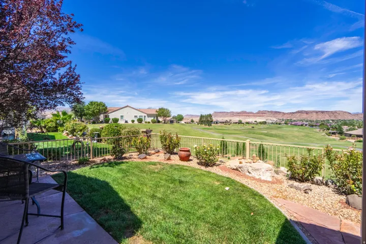 Expansive outdoor living area featuring a stone patio, manicured lawn, and mature landscaping