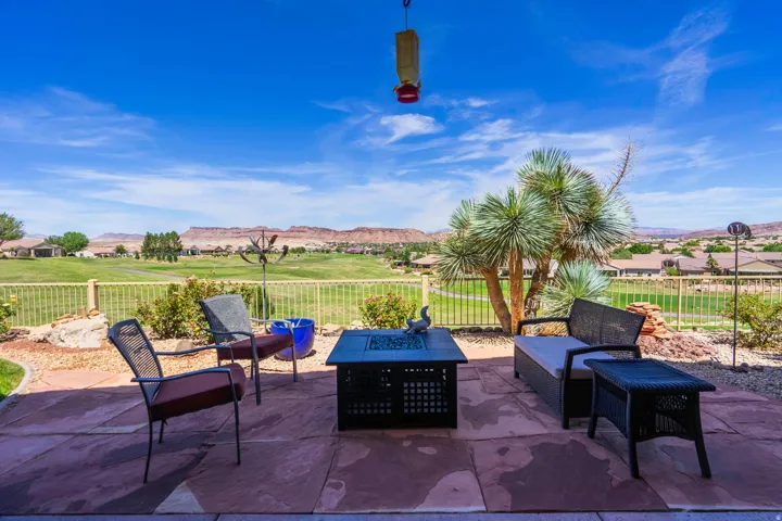 Expansive patio featuring large format pavers, a decorative fire pit, and a low fence overlooking a golf course