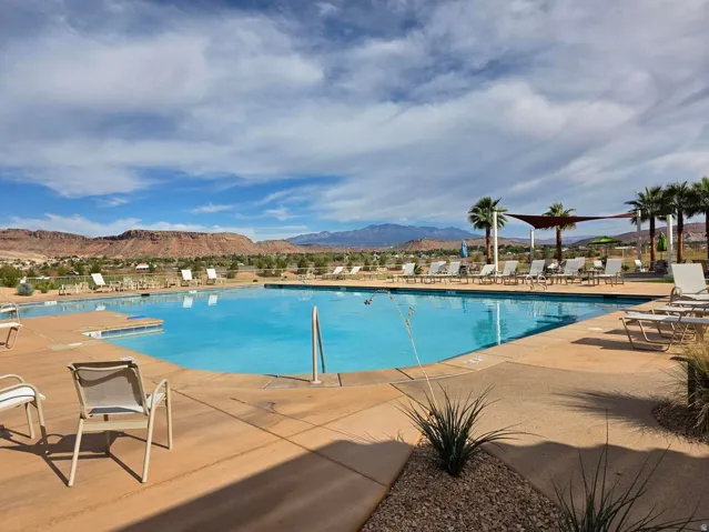Expansive swimming pool with integrated seating, surrounded by a concrete deck and desert landscaping