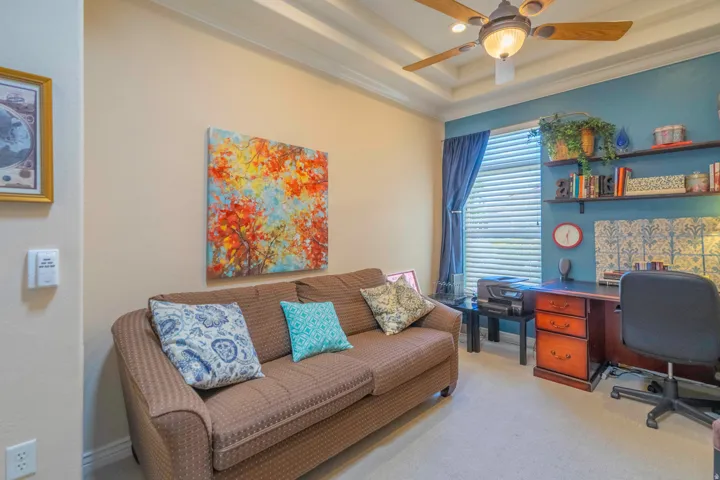 Versatile bonus room featuring a coffered ceiling with integrated lighting, neutral wall-to-wall carpeting, and built-in shelving with display space
