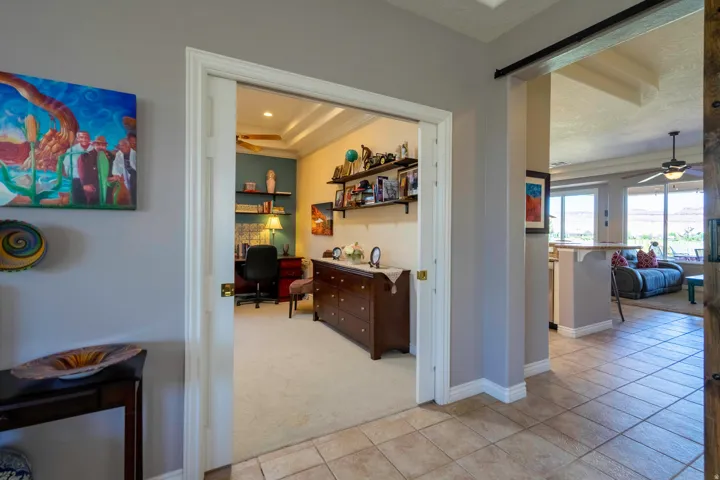 Elegant hallway with neutral tile flooring leading to multiple rooms featuring white trim work and ceiling details