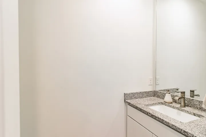 Built-in vanity with a granite countertop, integrated sink, and brushed nickel faucet