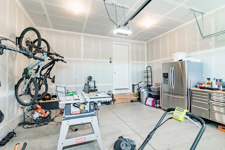 Concrete flooring, overhead lighting, garage door opener, and a white interior door