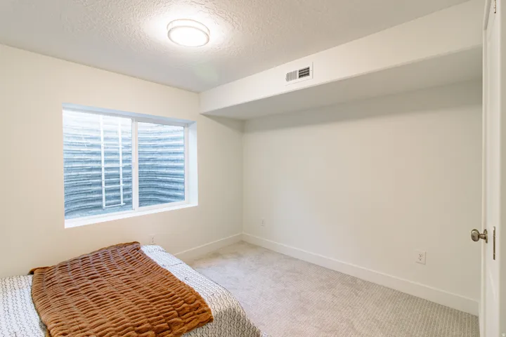 Recessed egress window, neutral carpeting, white wall paint, flush-mount ceiling light