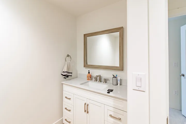 White vanity with brushed gold hardware, integrated sink, and a framed mirror