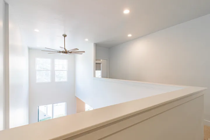 Two-story interior with recessed lighting, a modern ceiling fan, and multiple windows