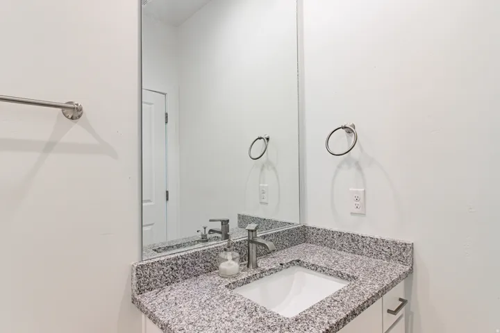 Vanity featuring a stone countertop, integrated sink, and brushed nickel fixtures