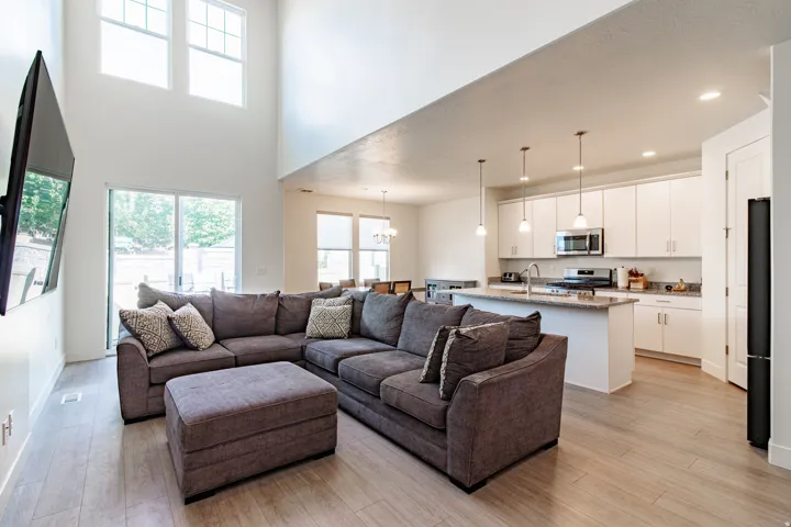 Vaulted ceilings, large sliding glass door, overhead lighting, kitchen island with built-in sink, and stainless steel appliances