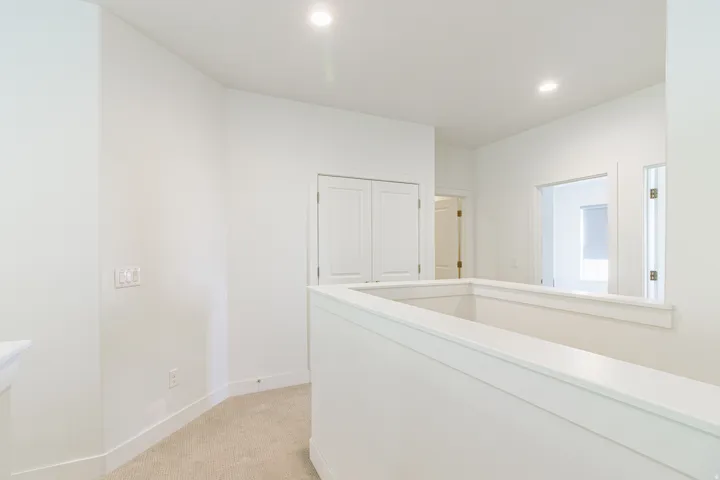 Hallway with recessed lighting, carpeted flooring, and a white painted railing