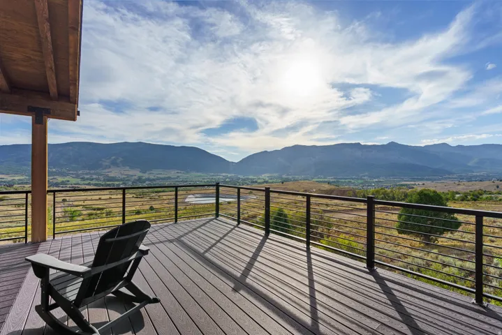 Expansive outdoor deck with composite decking, cable railing, and a large roof overhang featuring exposed wood beams