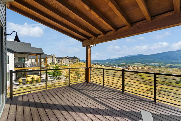 Expansive covered deck with composite decking, horizontal cable railings, and a wood-finished ceiling