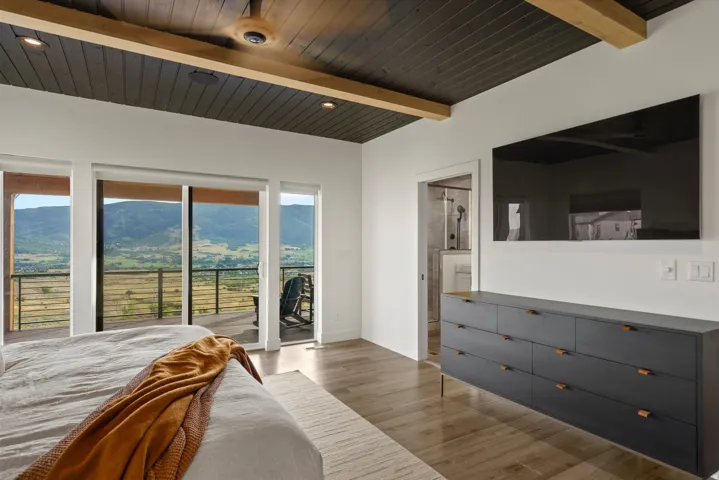Wood-finish flooring with a dark wood plank ceiling featuring exposed beams and recessed lighting