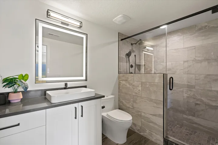 Vanity with a rectangular vessel sink, dark countertop, and white cabinetry
