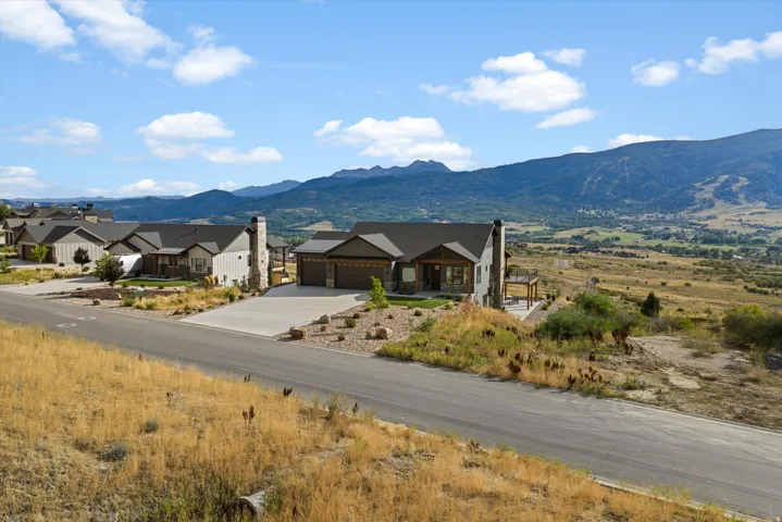 Contemporary-style residence with a two-car garage, stone chimney, and an elevated patio