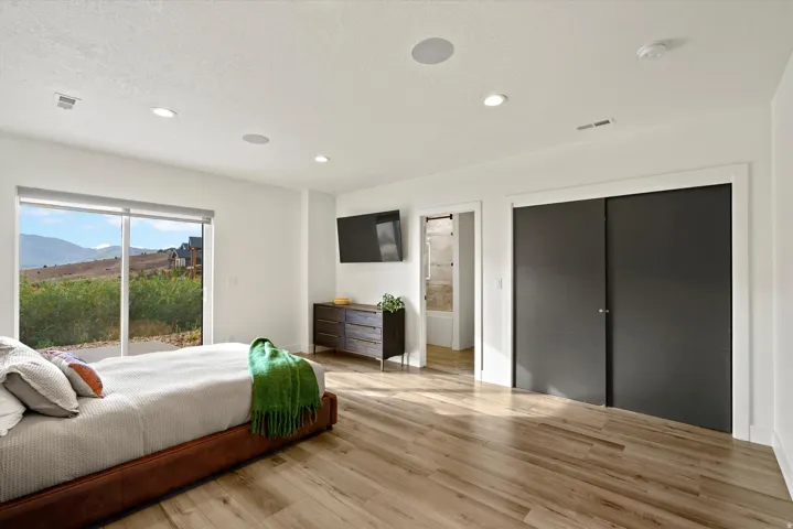 Large sliding glass doors, recessed lighting, wood-finish flooring, built-in ceiling speakers, and dark sliding closet doors