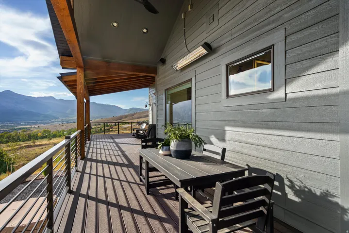 Expansive outdoor deck featuring wood-finish flooring, a wood-beamed ceiling, recessed lighting, and a cable railing system