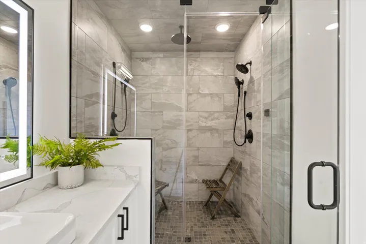 Glass-enclosed shower with matte black fixtures and a rain showerhead