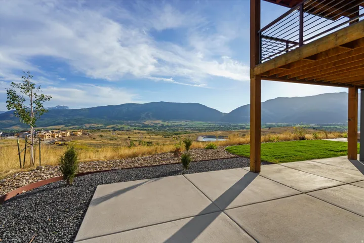 Concrete patio with expansive mountain scenery, landscaped gravel, and a manicured lawn