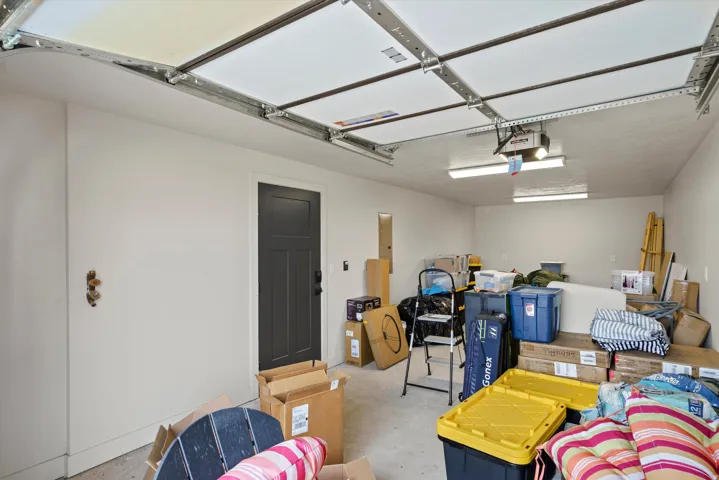 Attached garage with a panel garage door, built-in lighting, and a dark-paneled interior door