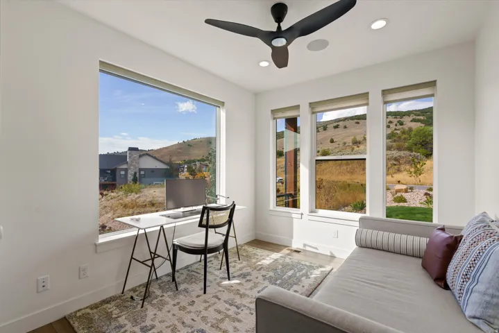 Expansive windows with surrounding landscape, recessed lighting, and a ceiling fan