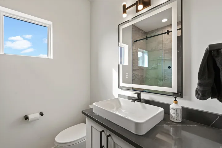 Floating vanity with a rectangular vessel sink, dark countertop, and matte black faucet