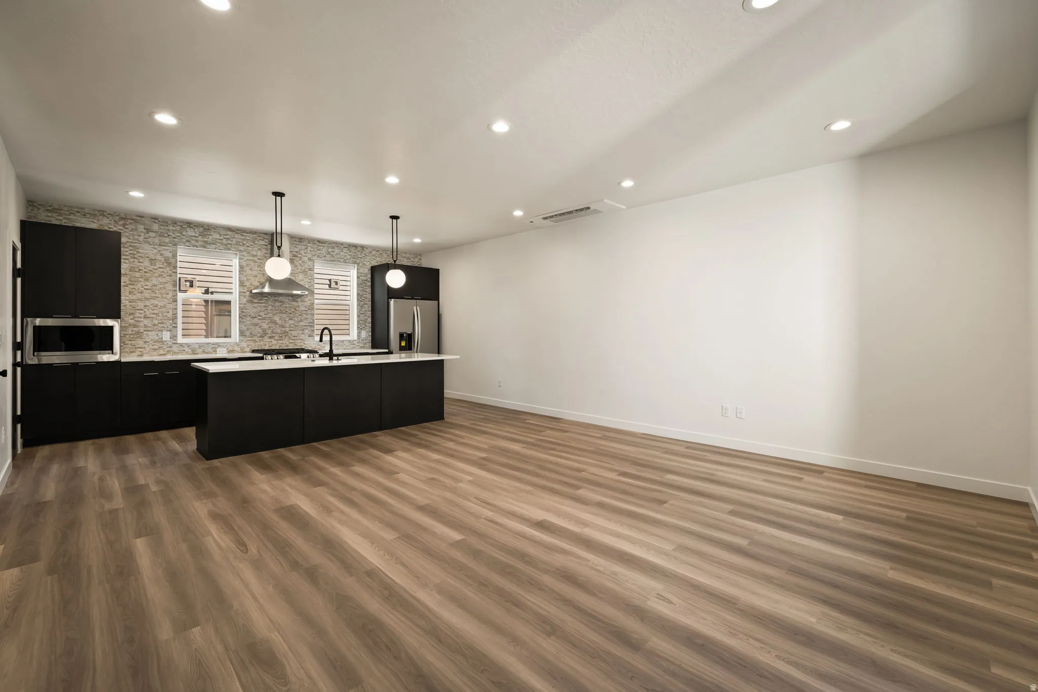 Open-concept living space featuring wood-finish flooring, recessed lighting, and a modern kitchen