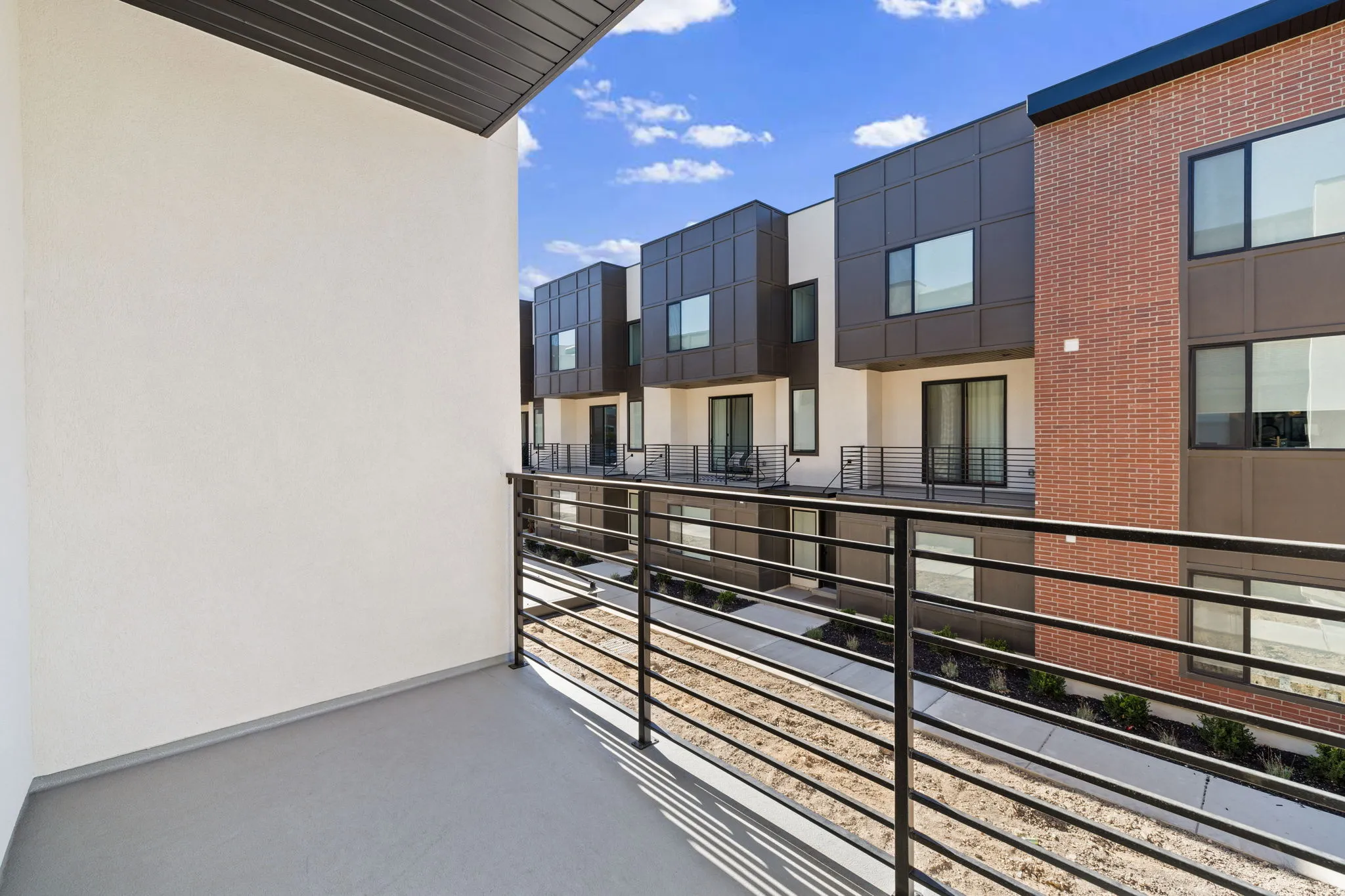 Private balcony with a metal railing, concrete flooring, and an overhead awning