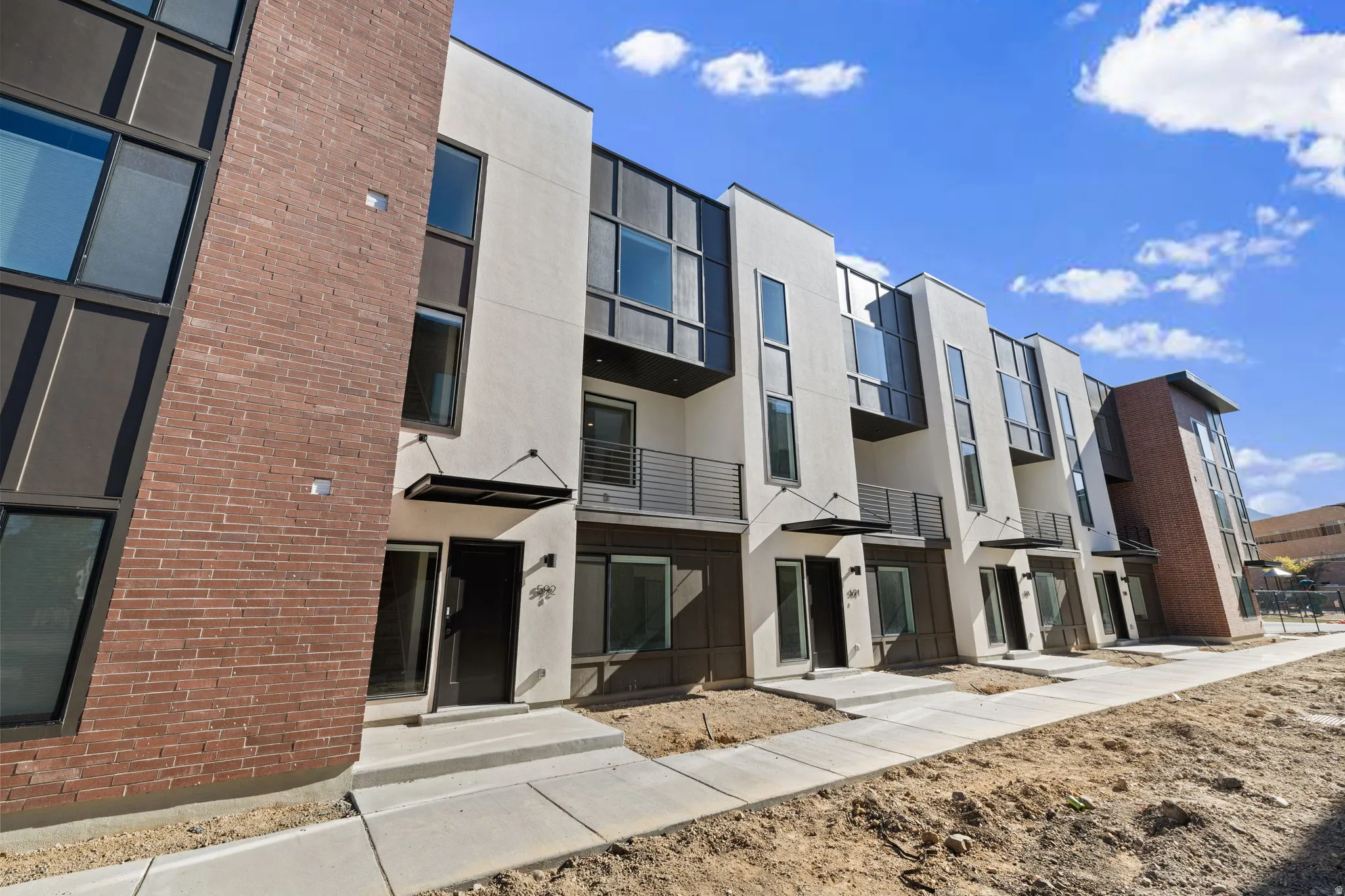 Contemporary townhome exterior featuring white stucco and brick accents