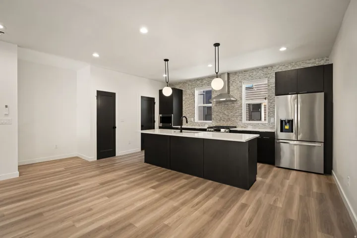 Open-concept kitchen with a central island, white countertops, dark wood-finish cabinetry, and stainless steel appliances