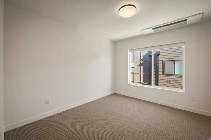 Recessed lighting, neutral wall tones, carpeted flooring, and a large window