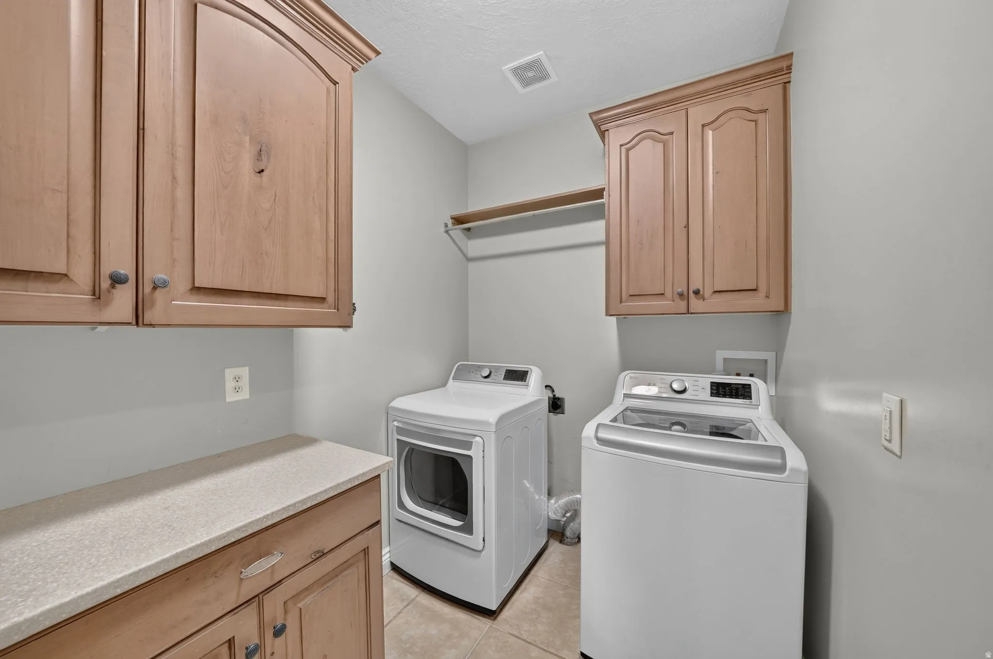 Laundry area featuring upper and lower cabinetry, a built-in countertop, and a storage shelf