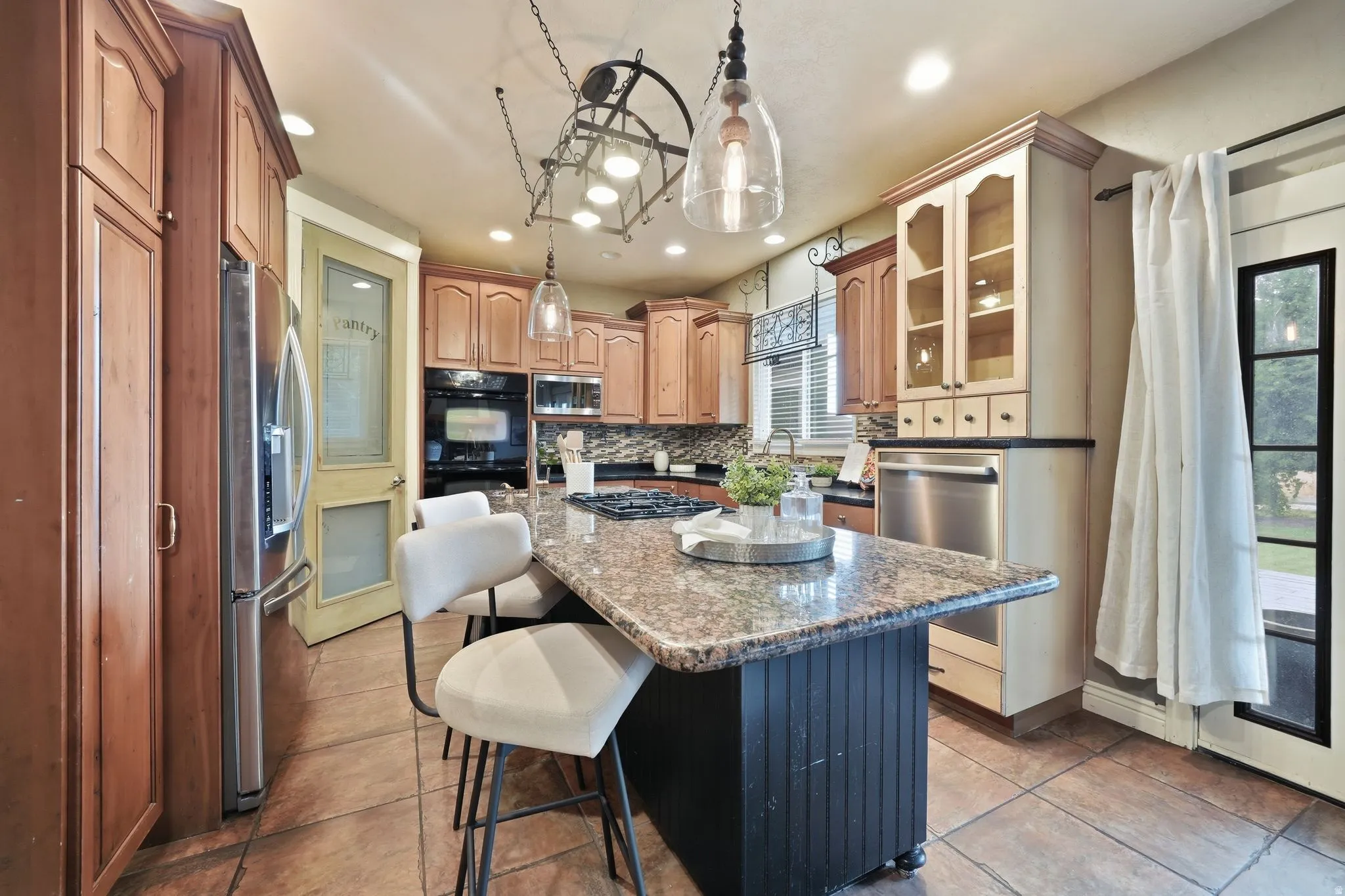 Kitchen featuring an expansive center island with stone countertop, tile flooring, stainless steel appliances, and built-in cabinetry