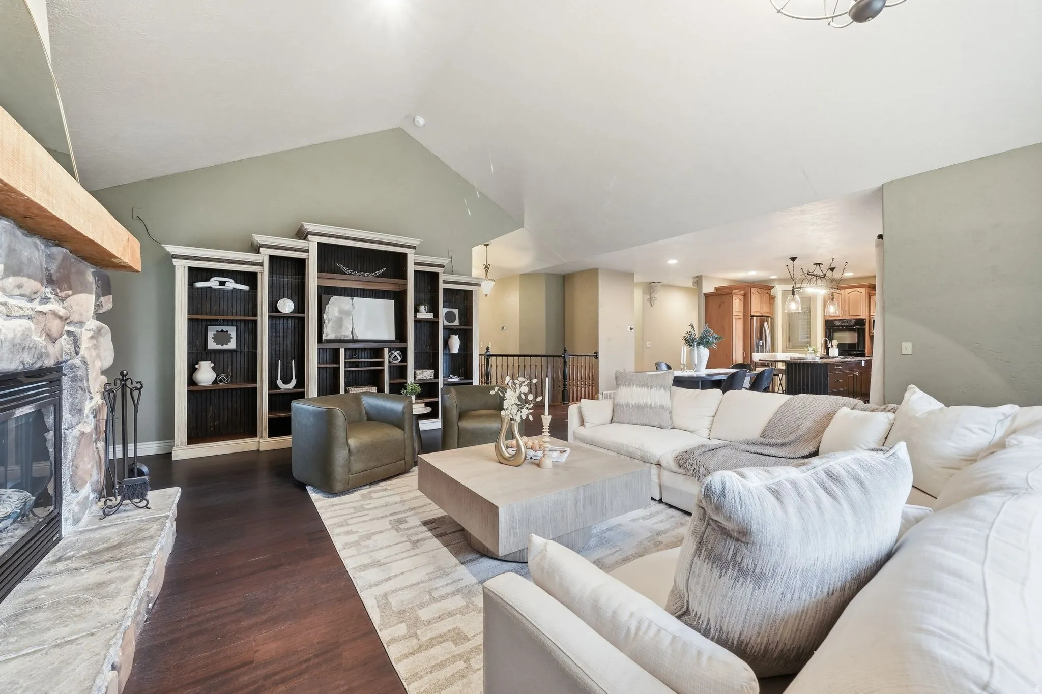 Expansive open-concept living area featuring soaring vaulted ceilings, abundant recessed lighting, and dark wood-finish flooring